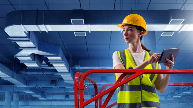 Woman engineer. Female industrial worker is monitoring ventilation shafts. Woman engineer holds electronic tablet. Industrial ventilation maintenance. Girl contractor monitors shaft vents.