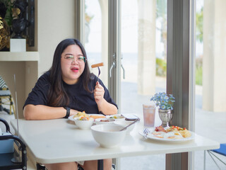 Curvy Asian woman enjoying breakfast with confidence and happiness.