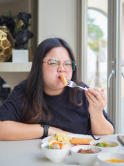Curvy Asian woman enjoying breakfast with confidence and happiness.