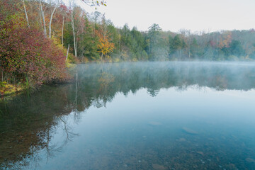 Beautiful Autumn Forest with Mountain Fog and A Lake