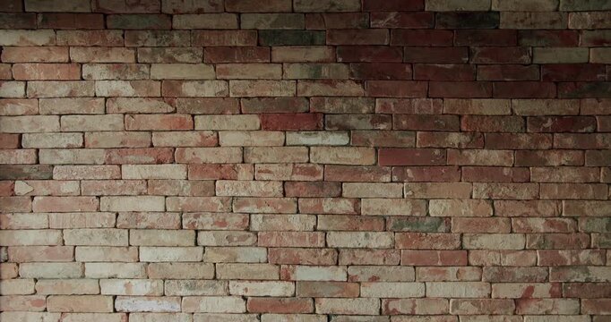Old brick wall of brown color in a modern apartment, damaged masonry as abstract background composition. textured surface of stucco texture with holes and scuffs. dolly camera movement.