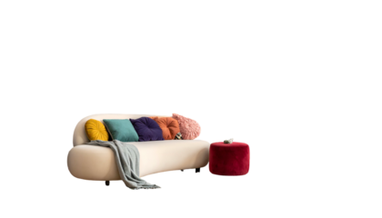 A modern, curved beige sofa with colorful pillows, a blanket, and a red ottoman