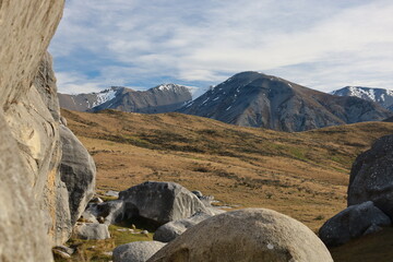 Dramatic limestone boulders, golden fields, and distant snow-capped mountains define the iconic landscape of Castle Hill (Kura Tawhiti), Canterbury, New Zealand, May 2025. A unique geological wonder © Chonlatit