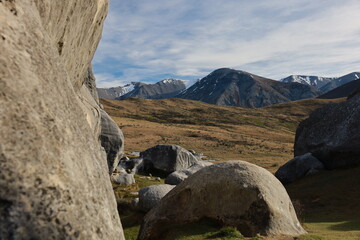 Dramatic limestone boulders, golden fields, and distant snow-capped mountains define the iconic landscape of Castle Hill (Kura Tawhiti), Canterbury, New Zealand, May 2025. A unique geological wonder © Chonlatit