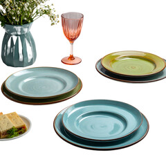 Stacked ceramic dinnerware and a glass of drink sit near a vase of flowers.