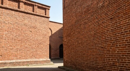 Brick building exterior; view between walls, arch visible deeper within structure