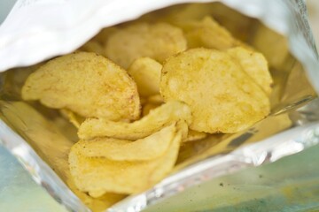 Golden crispy potato chips inside a clean white foil bag