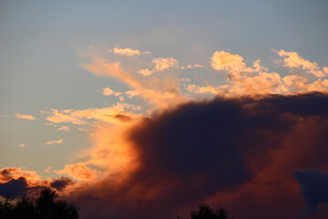 Dramatic sunset clouds with vibrant orange and deep purple hues, contrasting against a soft blue sky. Beautiful natural light and atmospheric beauty
