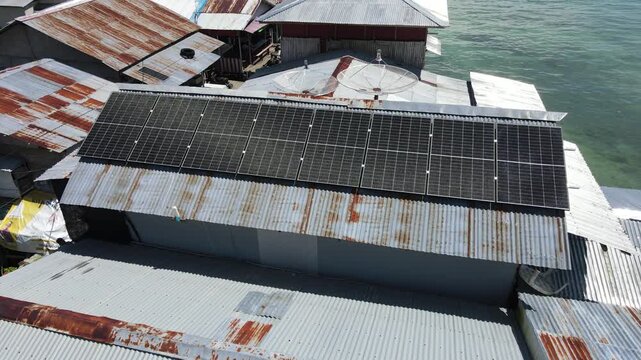 Aerial view of solar panels on rusty metal roofs near the sea
