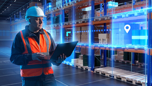Warehouse management. Logistics, supply chain and inventory control. Worker in protective vest and helmet uses laptop in a smart warehouse with digital interface for cargo tracking 
