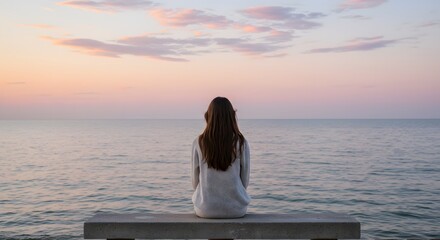 A person sits on a bench, facing the ocean at dusk, sky painted with pastels