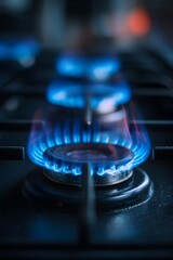 Close up view of a bright blue natural gas flame burning intensely on a modern kitchen stove top burner providing heat for cooking