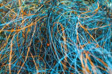 abstract collection of blue and orange cables or fibers that are intertwined and form a random pattern.