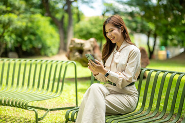 Woman smiling using smartphone on park bench