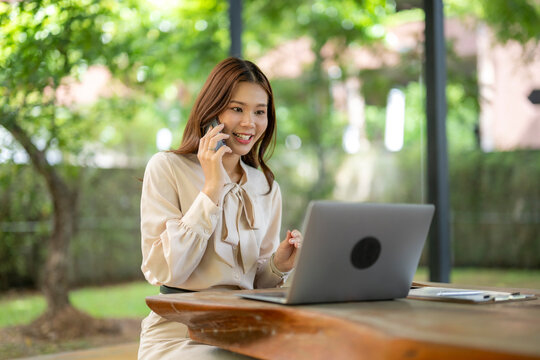 Woman talking on phone and working on laptop outdoors