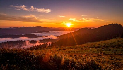 Sunset over mountain range with clouds filling valley, radiating light