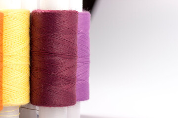 Multicolored sewing reels with threads stand on a white background. taken in close-up with space for text