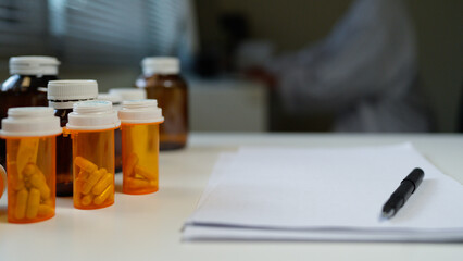 Blank Paper with Pen and A Bottle of medicine pills on Table at office room