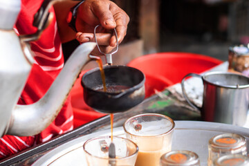 Authentic street food experience with chai being poured in glasses from kettle, perfect for travel blogs, cultural insights, and vibrant depictions of India's rich traditions and daily life