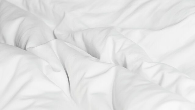 Close up soft white wrinkled duvet bed sheet texture, minimal background for comfort, cleanliness, and relaxation concept in bedroom or hotel interior