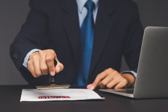 Businessman stamping rejected document on office desk.