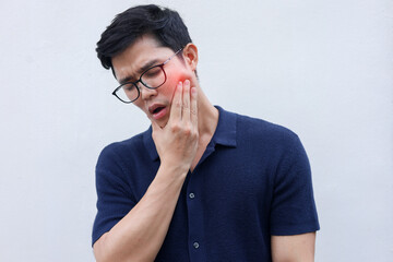 close up young asian man frown and use hand to massage on cheek after feeling pain or hurt from tmj...