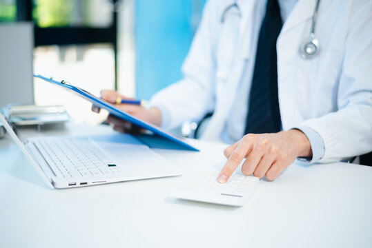 Healthcare costs and fees concept.Hand of smart doctor used a calculator and smartphone, tablet for medical costs at hospital