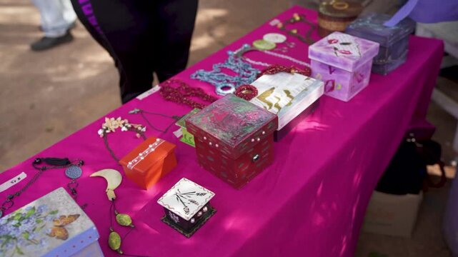 Handmade jewelry and decorative boxes displayed on table at local craft fair.
