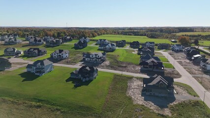 An aerial view of a new housing development under construction in Caledon, Ontario. The shot shows a mix of completed homes, new builds, and empty, undeveloped lots.