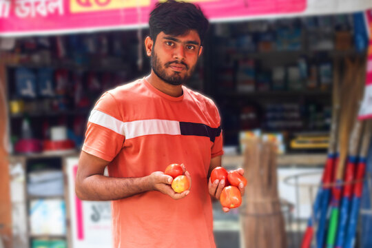 Young man confidently chooses fresh tomatoes at local market for healthy cooking, showcasing vibrant colors and supporting local farmers, a taste of summer