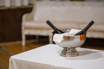 Elegant Celebration Preparation Two Champagne Bottles Chilled in Ice Bucket with White Cloth Ready for Festive Event Sophisticated Hospitality Setting