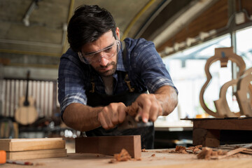 Focused carpenter planing wooden surface in workshop showing strength precision and craftsmanship skill