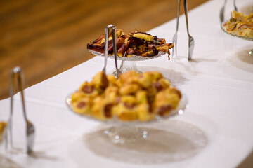 A Delicious Spread of Assorted Appetizers and Desserts Served at a Formal Event or Buffet Gathering Featuring Various Savory and Sweet Bites Arranged Artistically on a White Tablecloth