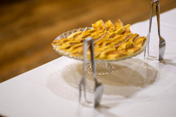 Delicious Homemade Apple Tart Baked Golden Brown Served Freshly Cut on a Clear Glass Cake Stand Ready for Guests to Enjoy at a Festive Gathering