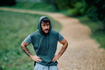 Athlete feeling exhaustion during outdoor training in a park. Fitness man taking a break from workout, catching his breath