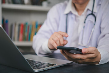 Doctor using mobile phone for telemedicine consultation. Medical professional with laptop providing online healthcare service for patient. Modern technology in medicine and health clinic concept.