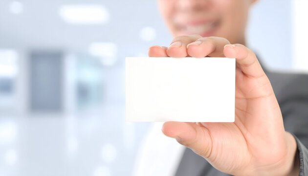 Businessman presents blank business card in bright office space, showcasing professionalism and opportunity for connection.