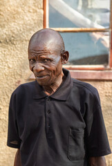 single african old man portrait, in the village, standing in front of the house, rural life in...