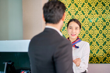 Female assistant air ground smile with businessman for checking the passport for release the ticket at airport check in counter.
