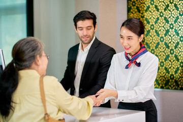 Scene of kind service with air ground staffs help the senior asian passenger to check in for travel by airline at airport check in counter.