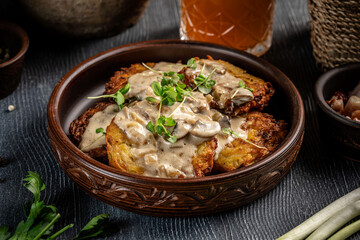 Potato pancakes with mushroom cream sauce in rustic bowl