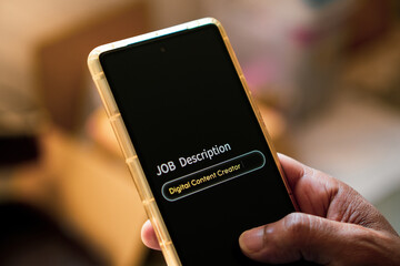 Man filling up job description on his mobile phone as digital content creator. Selective focus on the display.