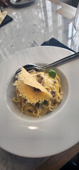 Creamy spaghetti carbonara with parmesan crisp and bacon on a white plate