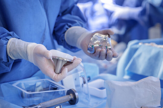 Surgeon holding knee implant components during total knee arthroplasty in sterile OR