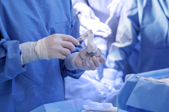 Surgeon applying bone cement to tibial implant during total knee arthroplasty