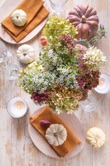Beautiful bouquet of autumn flowers in pumpkin on festive dining table