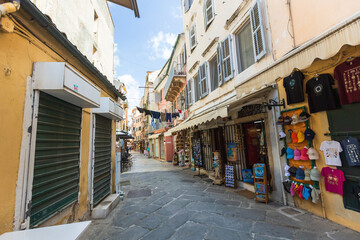 Colorful Corfu Town street with pastel facades, hanging laundry, and souvenir shops.