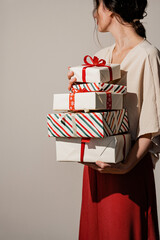Person carrying multiple Christmas presents with red ribbon bow decorations