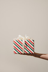 A single wrapped Christmas present with ribbons held in one hand