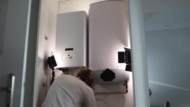 Man at home checking heating boiler and water heater before turning on the heating season ensuring everything functions correctly and efficiently